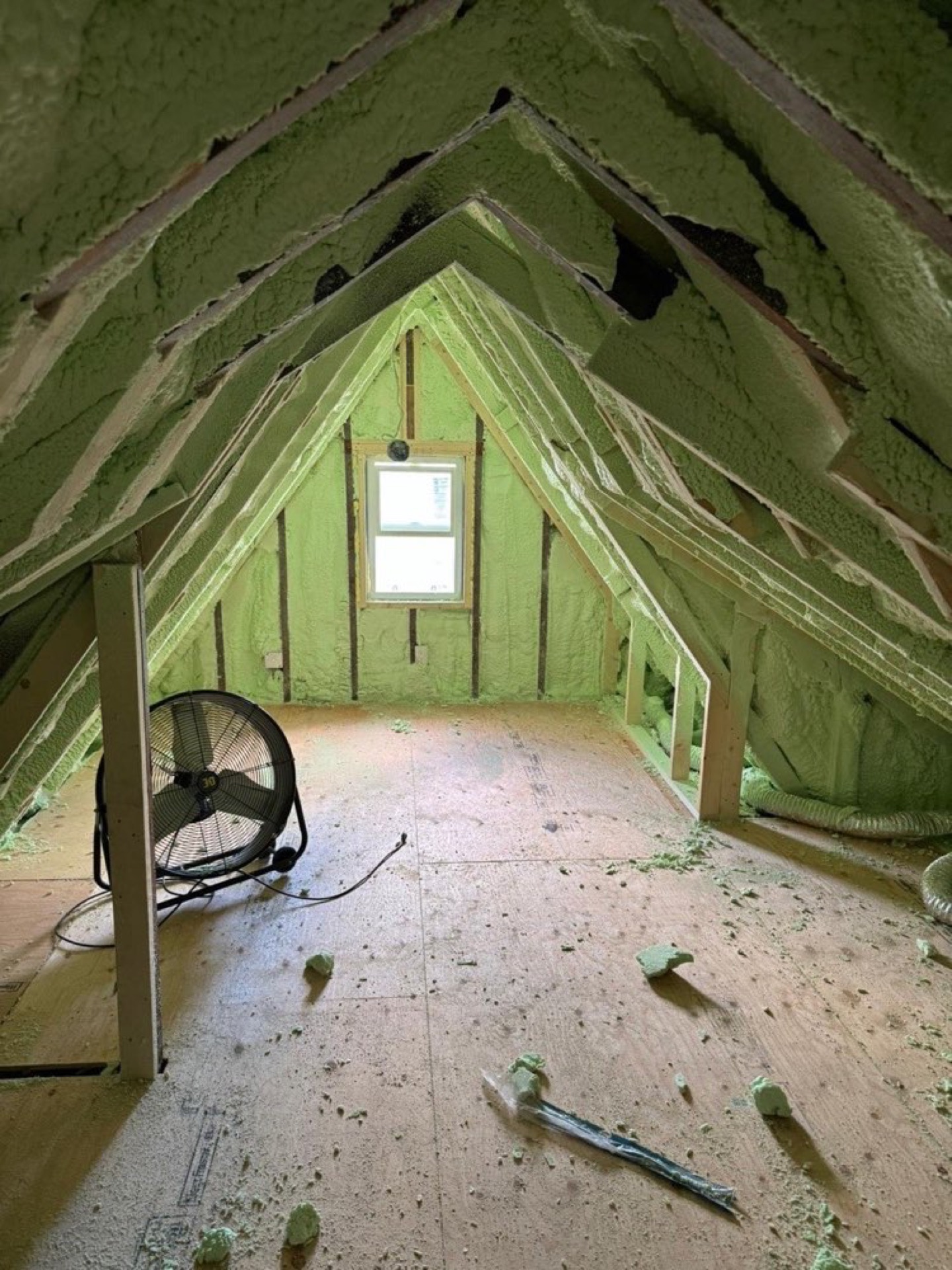 Green-coloured foam visible between roof framing in an attic work area.